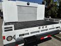 A white 2017 Ford F-550 flatbed truck with a textured metal surface on the cargo area and circular lights at the rear