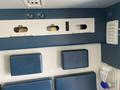 Interior of a 2011 Chevrolet Express featuring two blue cushioned seats and wall-mounted controls for lights and air conditioning