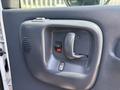 The interior door handle and control panel of a 2005 GMC C7500 Topkick featuring a handle a lock button and a speaker grille