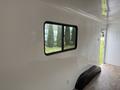 Interior view of a 2025 Shuttle Office featuring a window on one wall and a curved bench along the floor