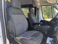 Two front seats of a 2020 RAM ProMaster 3500 one has an adjustable armrest both have a gray fabric upholstery with headrests and a spacious configuration