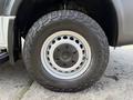 A close-up of a wheel and tire from a 2017 Mercedes-Benz Sprinter showcasing a metallic rim and rugged tread pattern on the tire