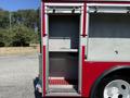 A red 1991 International 4600 fire truck with an open storage compartment revealing empty shelves and a rubber mat on the floor