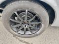 A close-up of a black alloy wheel with a multi-spoke design and a tire marked with the brand name showing the tread pattern