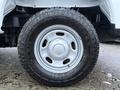A close-up of a white wheel and tire from a 2023 Ford F-250 showcasing the tread pattern and metallic rim design