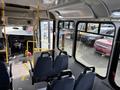 Interior view of a 2018 Chevrolet Express bus showing rows of blue seats and a driver area with control panel and steering wheel