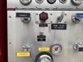 A control panel for a 2002 GMC C7500 featuring various gauges switches and labels for discharge valves and a speed counter