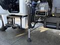 Close-up of a 2015 Hino 358 showing the hydraulic stabilizer leg in a lowered position next to the vehicle's frame with visible components and controls