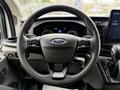 Steering wheel of a 2022 Ford Transit with the Ford logo cruise control buttons and a key attached to the ignition switch
