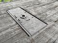 A weathered wooden surface featuring a rectangular metallic access panel with various screws and a circular lock mechanism in the center