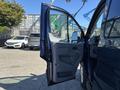 A blue 2016 Ford Transit 150 with the passenger door open showing the interior door panel and seat