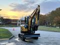 A 2023 Sany SY35U excavator with a yellow and black color scheme is positioned on a paved surface equipped with a front blade attachment