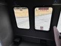 A 2014 Ford E-350 interior with two windows and a gray floor showing a wheelchair accessible space and signage for emergency exit