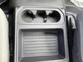 A car's center console featuring two cup holders and a flat storage compartment below