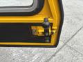 Detail of a 2004 Bombardier SW48 door latch mechanism featuring a yellow latch and black button against a textured black surface