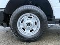 A close-up of a 2023 Ford F-250 rear tire showing a rugged all-terrain tread pattern and a white wheel rim