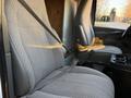 A 2015 GMC Savana's front seats with gray upholstery and seat belts visible