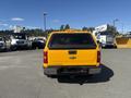 A yellow 2013 Chevrolet Silverado 1500 pickup truck viewed from the back with a visible Chevrolet logo and rear bumper features