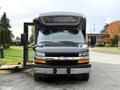 A black 2019 Chevrolet Express with an open door and a large front windshield is parked with its headlights visible
