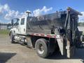A white 2014 International 7400 dump truck with a black dump bed and rear hydraulic lift system parked on a gravel surface