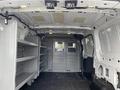 Interior of a 2017 Ford Transit van featuring shelving units on one side and a partition with a mesh window separating the front cabin from the cargo area