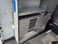 A silver metal shelving unit with five black drawers and a closed cabinet door is inside the cargo area of a 2017 Mercedes-Benz Sprinter