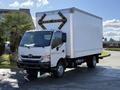 A white 2014 Hino 195 truck with a boxy cargo area and distinctive yellow lights shaped like an arrow on the back