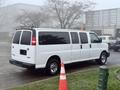 A white 2016 GMC Savana van with tinted windows and multiple passenger doors parked next to a traffic cone