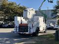 A white 2006 Freightliner M2 106 utility truck with a raised bucket lift and a sign reading "FREQUENT STOPS" on the back