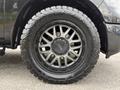 Close-up of a black wheel with an intricate rim design mounted on a rugged tire, showcasing details of the wheel's surface and tread pattern