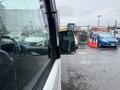 A 2010 Suzuki Carry seen from the side with its driver side mirror in focus showing raindrops on the surface