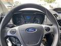Steering wheel of a 2019 Ford Transit featuring a Ford logo and control buttons with a digital dashboard and gauges visible behind