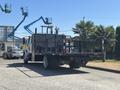 A 2011 International 4300 truck with a flatbed and safety railing at the rear viewed from the side