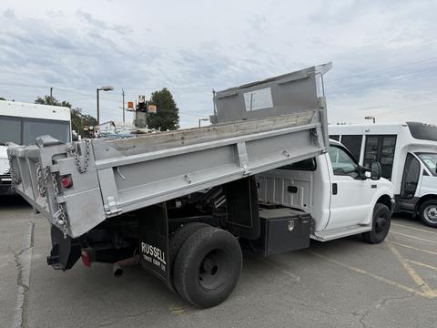 A white 2004 Ford F-350 SD with a raised dump bed positioned at an angle