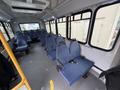 Interior of a 2017 Chevrolet Express showing blue fabric seats arranged in rows with a clear aisle and handrails visible