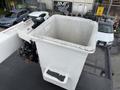 A white bucket attached to a lift on a truck with controls visible at the base