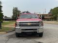 A red 2015 Chevrolet Silverado 3500HD with chrome accents and a prominent front grille stands facing the viewer