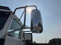 A 2020 Peterbilt 330 truck's side mirror reflecting sunlight and nearby structures
