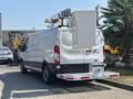 A white 2019 Ford Transit 350 van with a service body and extended ladder rack mounted on the roof