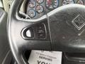 Close-up of the steering wheel of a 2014 International 7500 featuring controls for cruise and throttle with a textured surface and a logo at the base