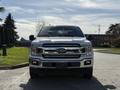 A 2018 Ford F-150 with a silver exterior and chrome grille is parked facing forward, showcasing its bold front design and headlights