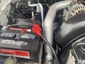 A 2005 Ford F-350 SD engine compartment showcasing the battery and various engine components with visible wiring and hoses