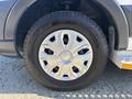 A close-up of a silver wheel on a 2017 Ford Transit-350 featuring a distinctive design with eight rounded openings and a black tire with clear tread patterns