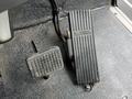 A black accelerator pedal on the right with a textured surface and a vertical throttle control pedal on the left with a smooth finish