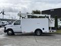 A 2017 Ford Econoline work van with a white exterior features a raised aerial lift on top and storage compartments on the side