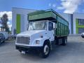 A 1997 Freightliner FL70 truck with a green cargo box attached to the flatbed and a white cabin