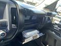 The interior of a 2014 GMC Sierra 1500 featuring a glove compartment opened to reveal a package inside and dashboard controls visible on the side