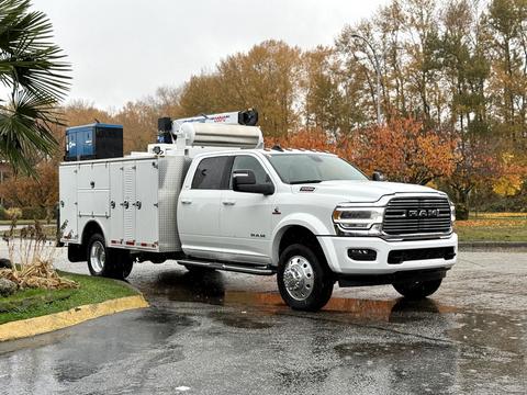White 2024 RAM 5500 truck with a utility bed and equipment on top parked on a wet surface