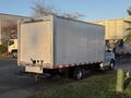 A white 2015 GMC Savana box truck is parked with its rear facing the viewer showing a plain back and side markings