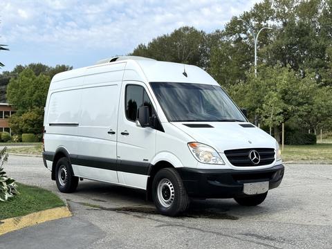 A 2012 Mercedes-Benz Sprinter van in white with a high roof and black accents parked in a residential area